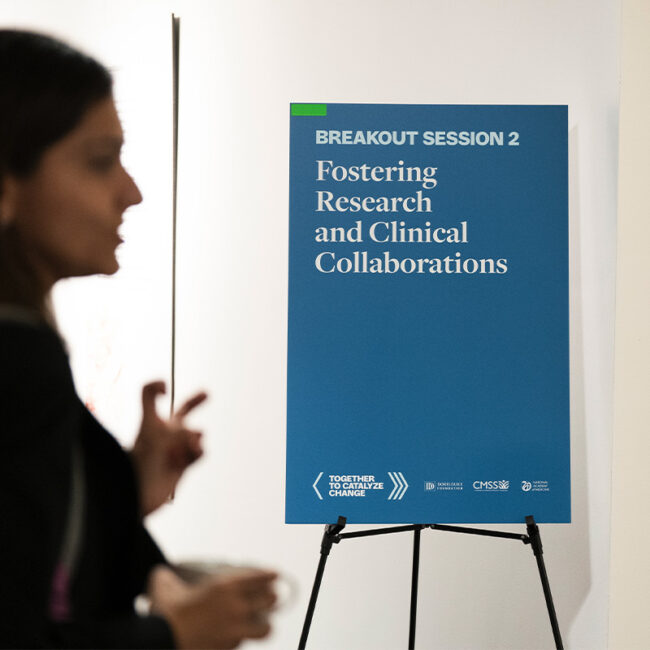A blue sign stating "Breakout Session 2: Fostering Research and Clinical Collaborations"